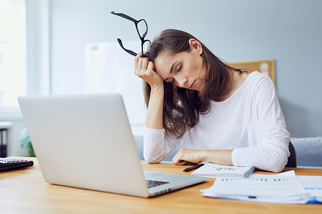 眠気で頭を抱える女性