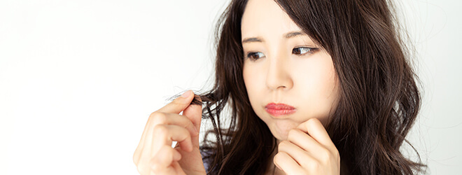 髪をいじりながら不満そうな女性